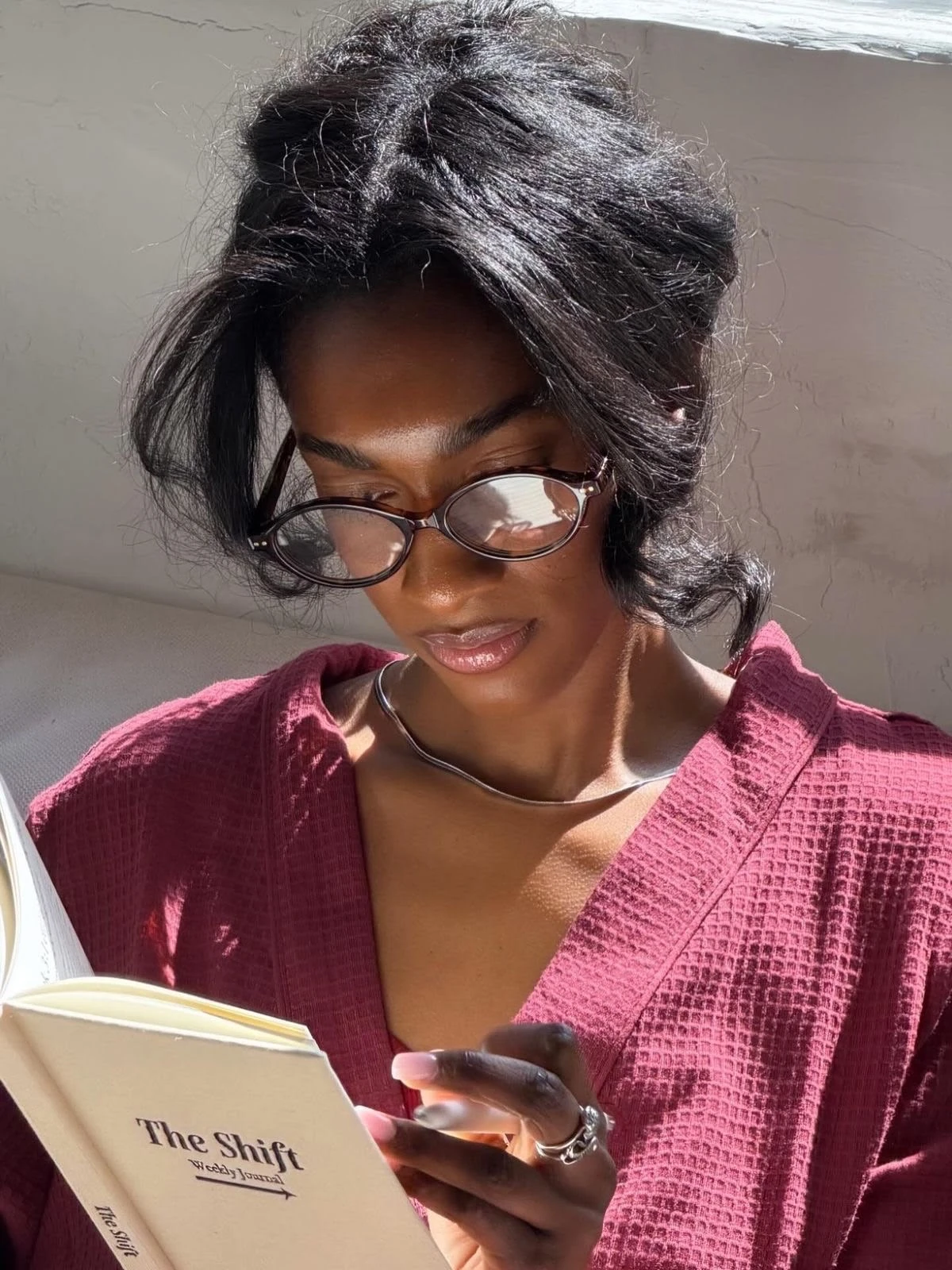 Sunlit lifestyle photograph of a woman reading a journal